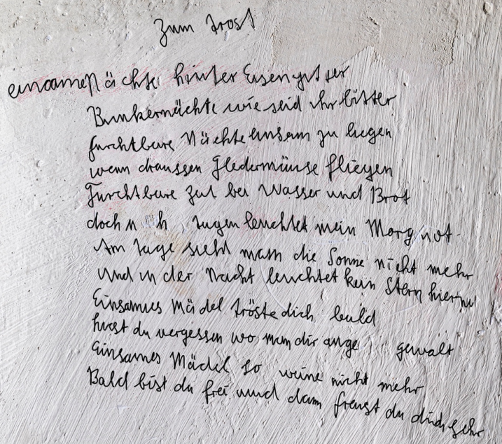 Auf dem Foto steht folgender Text: Einsame Nächte hinter Eisengitter Bunkernächte wie seid ihr bitter furchtbare Nächte einsam zu liegen wenn draussen Fledermäuse fliegen furchtbare Zeit bei Wasser und Brot doch in den Augen leuchtet mein Morgenrot am Tage sieht man die Sonne nicht mehr und in der Nacht leuchtet kein Stern hierher einsames Mädel tröste dich bald hast du vergessen wo man dir angetan Gewalt einsames Mädel so weine nicht mehr denn bald bist du frei und dann freust du dich sehr